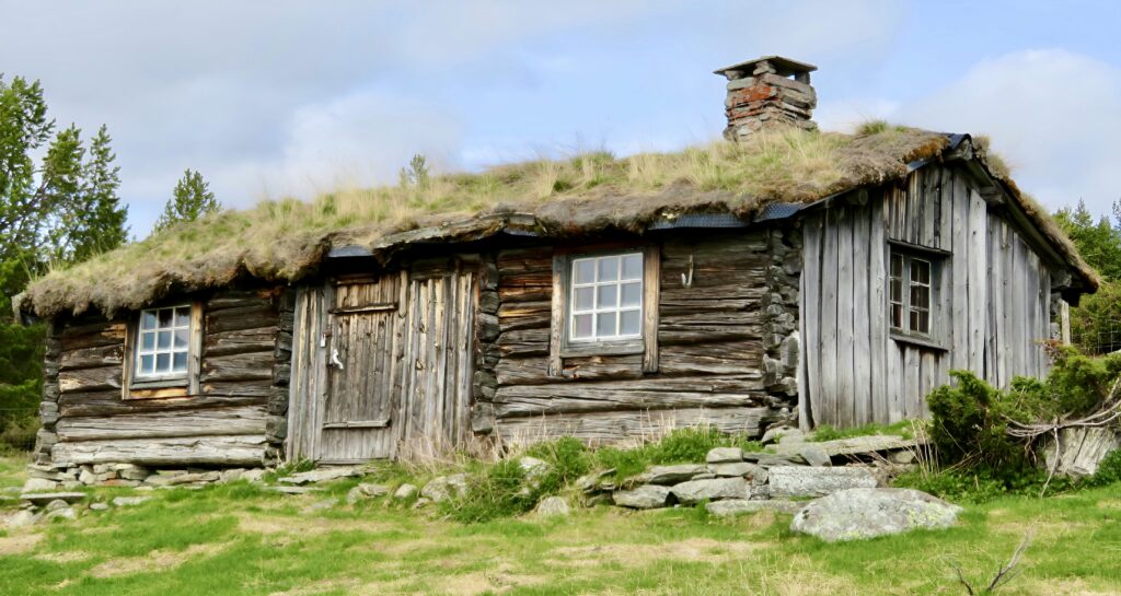 प्रधानमंत्री ग्रामीण आवास योजना: एक नई दिशा An old log cabin with a grass roof