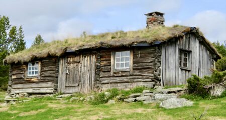 प्रधानमंत्री ग्रामीण आवास योजना: एक नई दिशा An old log cabin with a grass roof